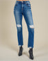 Blue jeans with distressed details worn by a person on a beige background