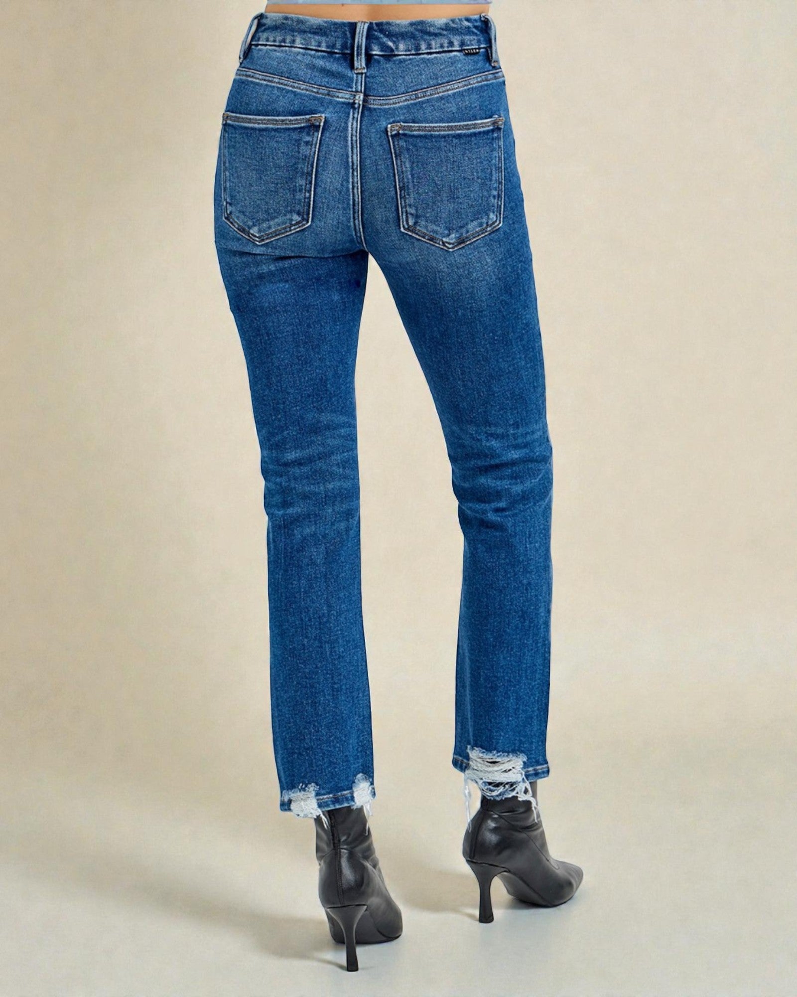 Blue jeans worn by a person on a beige background