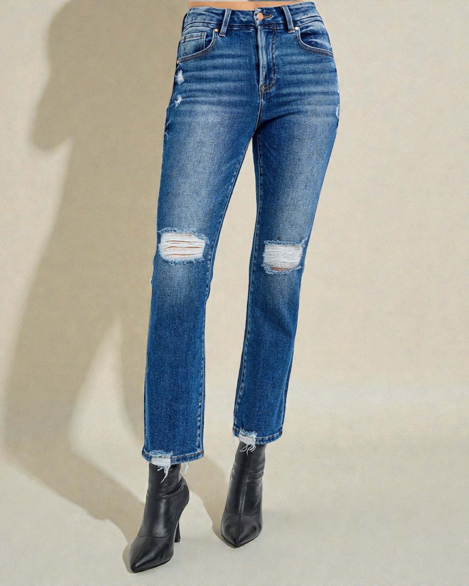 Blue distressed jeans worn by a person on a beige background