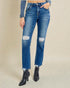 Person wearing blue jeans with distressed details on a beige background