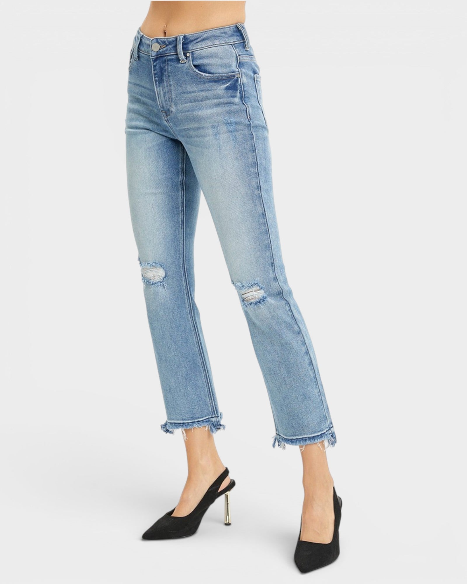 Light wash blue distressed cropped jeans with frayed hems, shown on a model wearing black slingback heels against a light gray studio background.