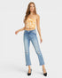 A woman modeling a yellow and white tiger-print strapless tube top paired with light-wash blue distressed cropped jeans and black heels, set against a plain light gray studio background.