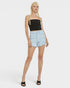 Woman wearing a black tank top and light blue denim shorts on a white background