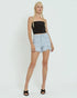 Person wearing a black tank top and light blue denim shorts on a white background