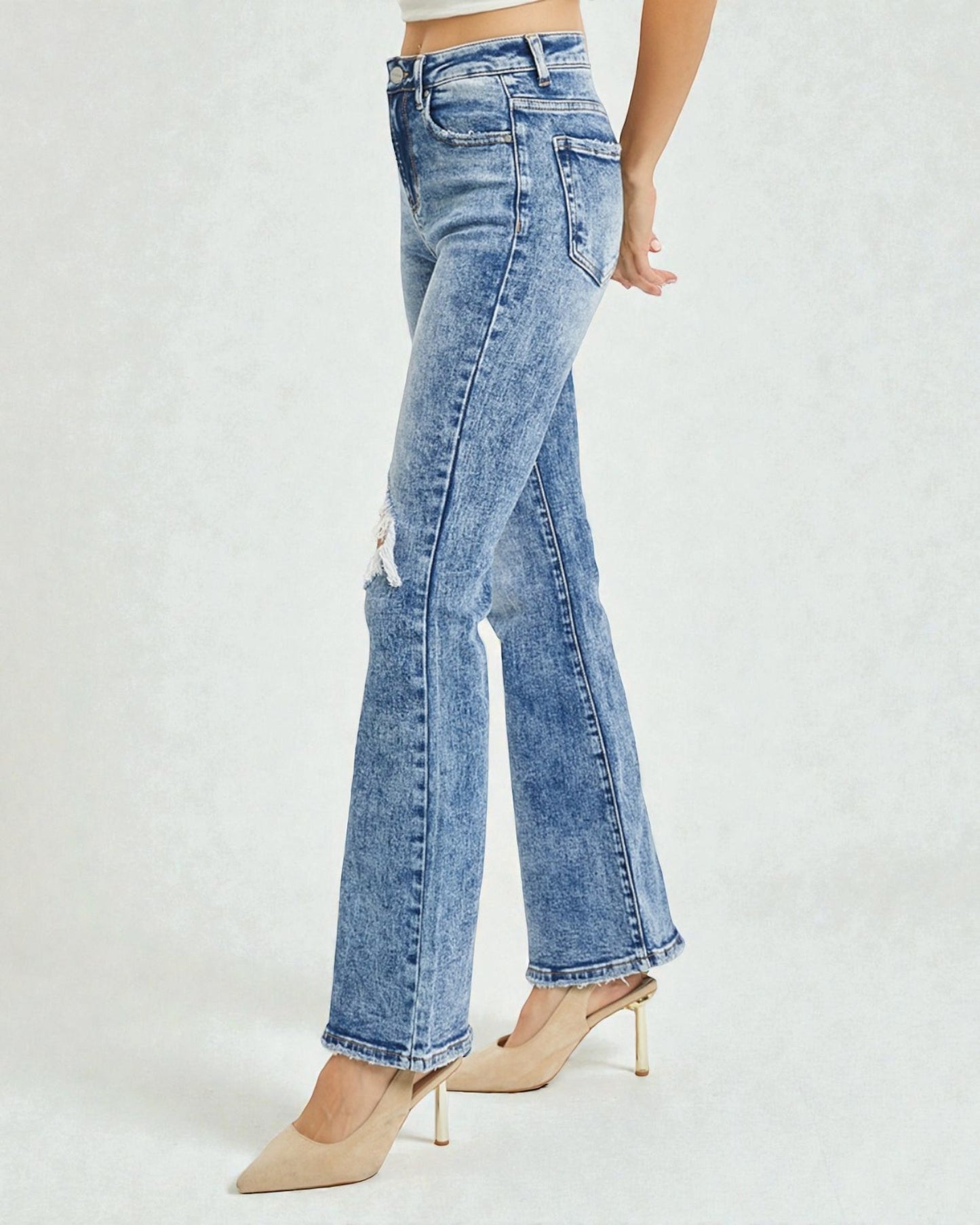 Blue flared jeans worn by a person on a white background