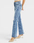 A model from the waist down wearing light blue high-waisted flare jeans with distressed details and beige pointed-toe stiletto heels, set against a plain light gray studio background.