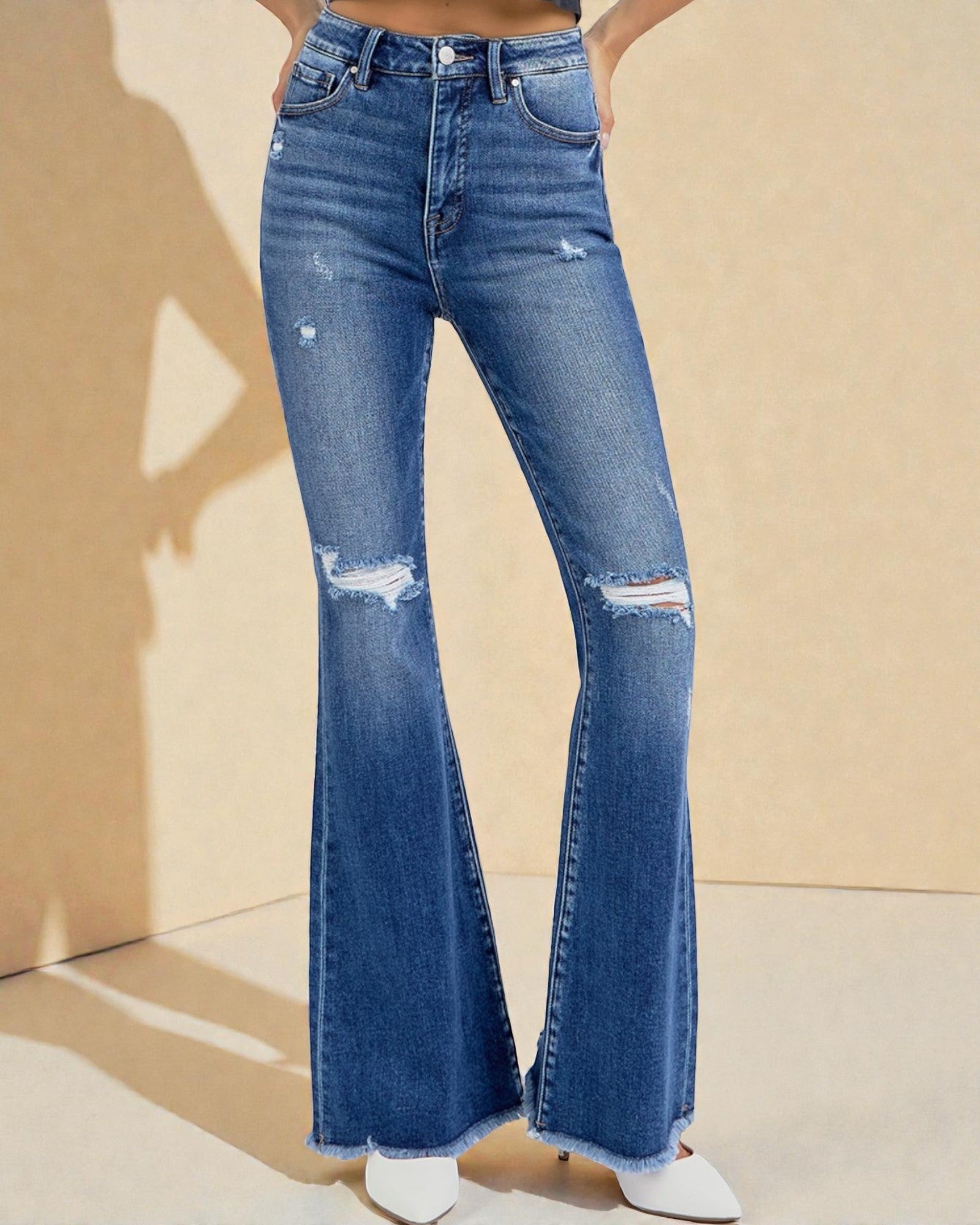 Blue flared jeans worn by a person on a beige background