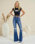 Woman wearing a black t-shirt and blue flared jeans standing in a minimalistic room.