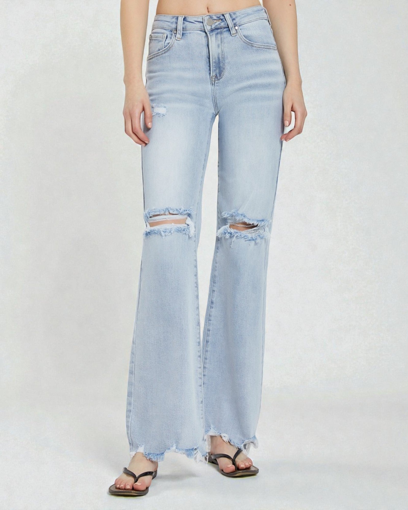 Light blue jeans with distressed details worn by a person on a white background