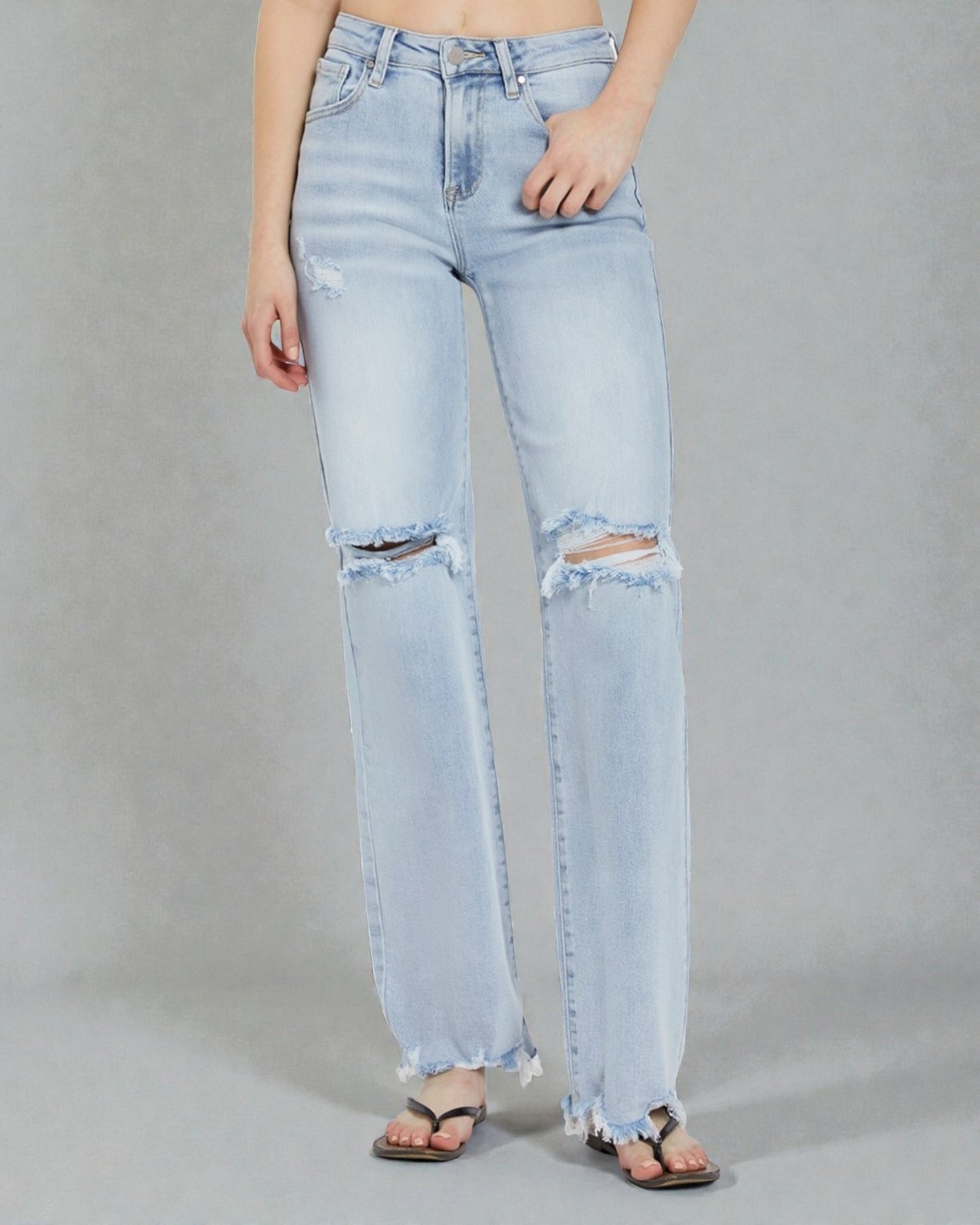 Light blue distressed jeans worn by a person on a gray background