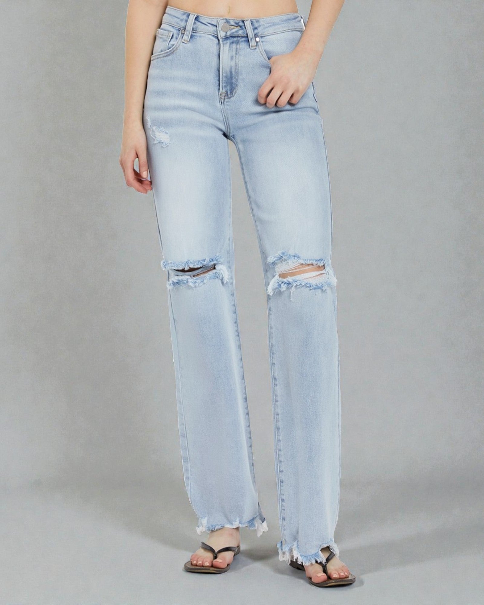 Light blue distressed jeans worn by a person on a gray background
