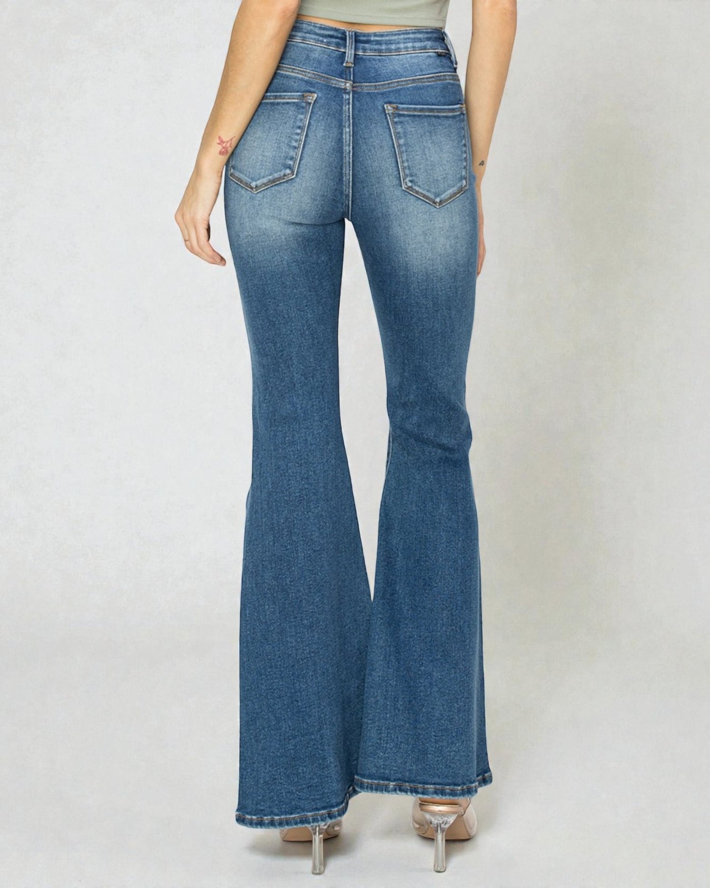 Flared jeans worn by a person on a plain background