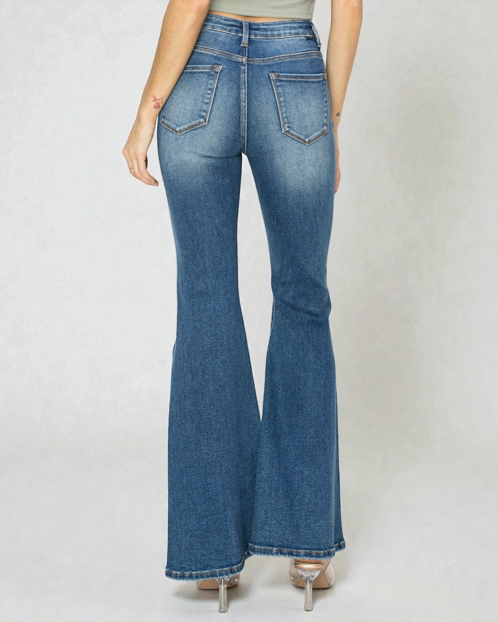 Flared jeans worn by a person on a plain background
