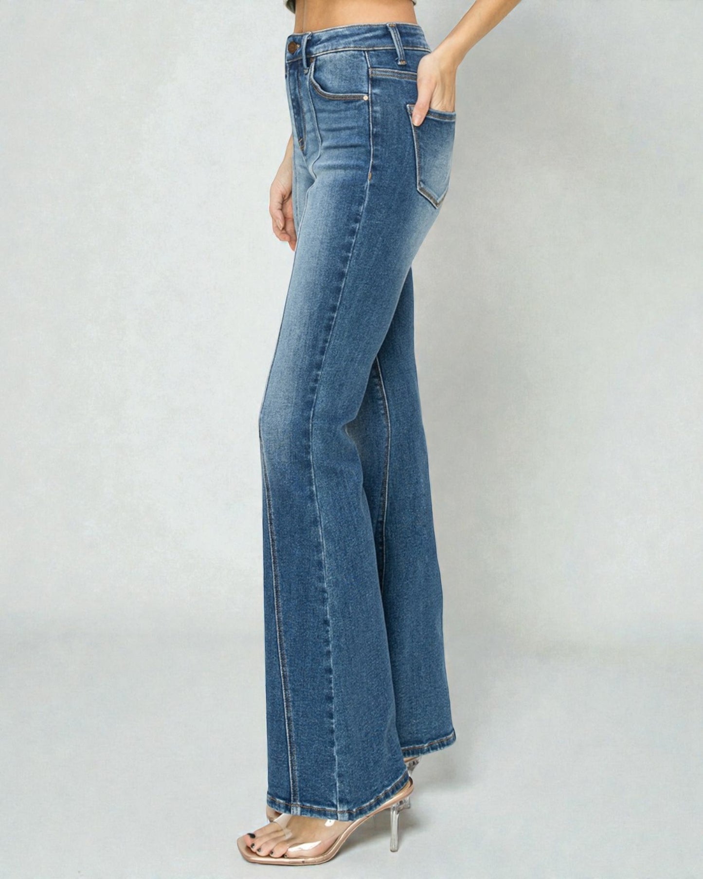 Blue jeans worn by a person on a plain background