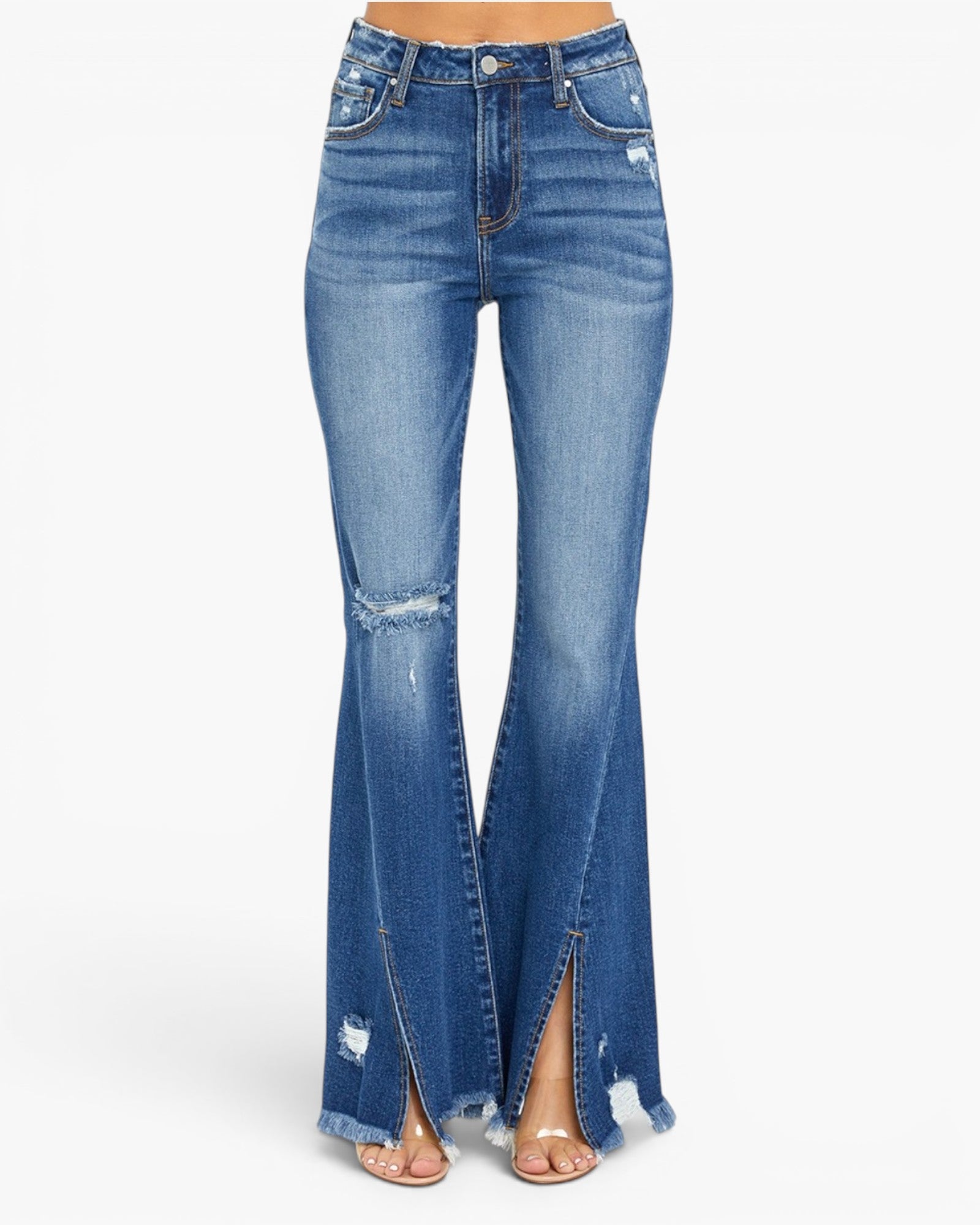 Medium wash blue denim flare jeans with a high-rise fit, distressed details, and front slit hems, shown on a model wearing clear high-heel sandals against a white background.