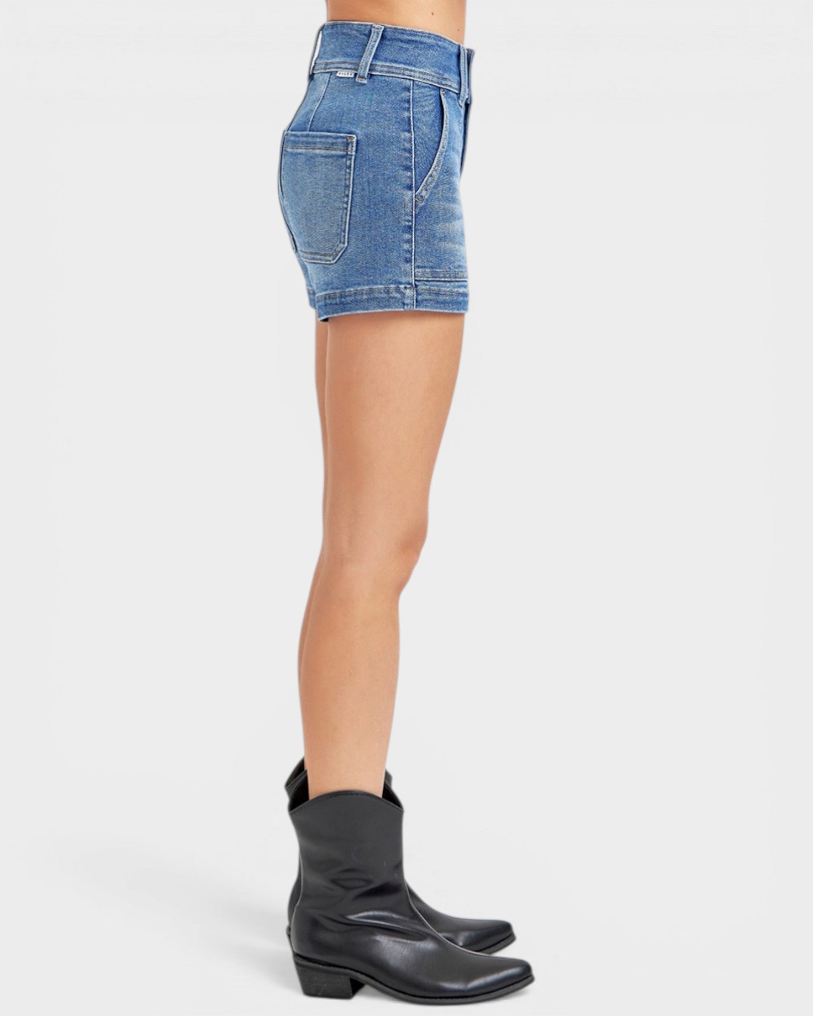 Person wearing blue denim shorts and black boots on a white background