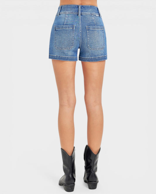 Person wearing blue denim shorts and black cowboy boots on a white background