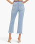 Back view of a model wearing light-wash blue cropped jeans with a frayed hem and a dark blue waistband, paired with clear-strap high-heeled sandals against a light gray studio background.