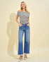 Woman wearing a striped top and blue jeans against a beige background