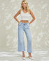 Woman wearing a white top and light blue jeans against a neutral background