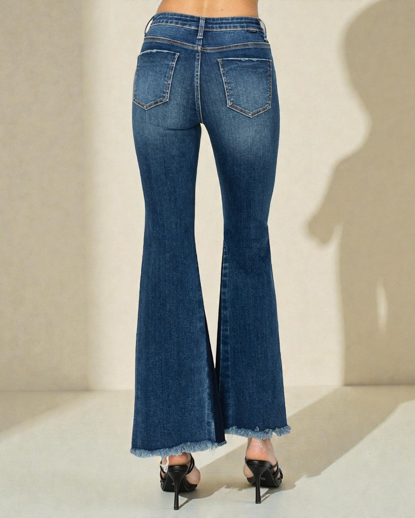 Blue flared jeans worn by a person on a neutral background