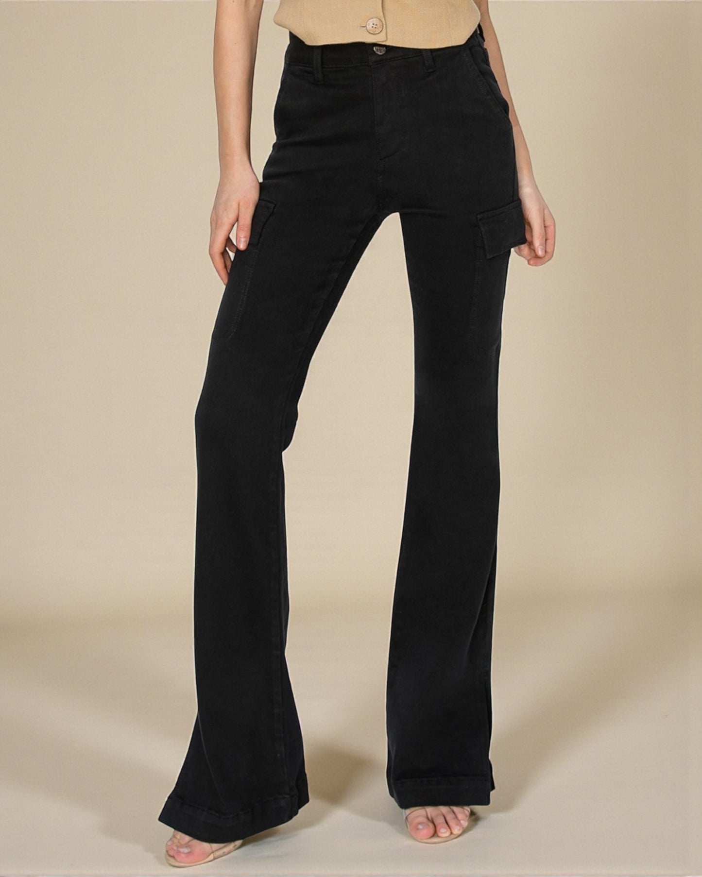 Black flared pants worn by a person on a beige background