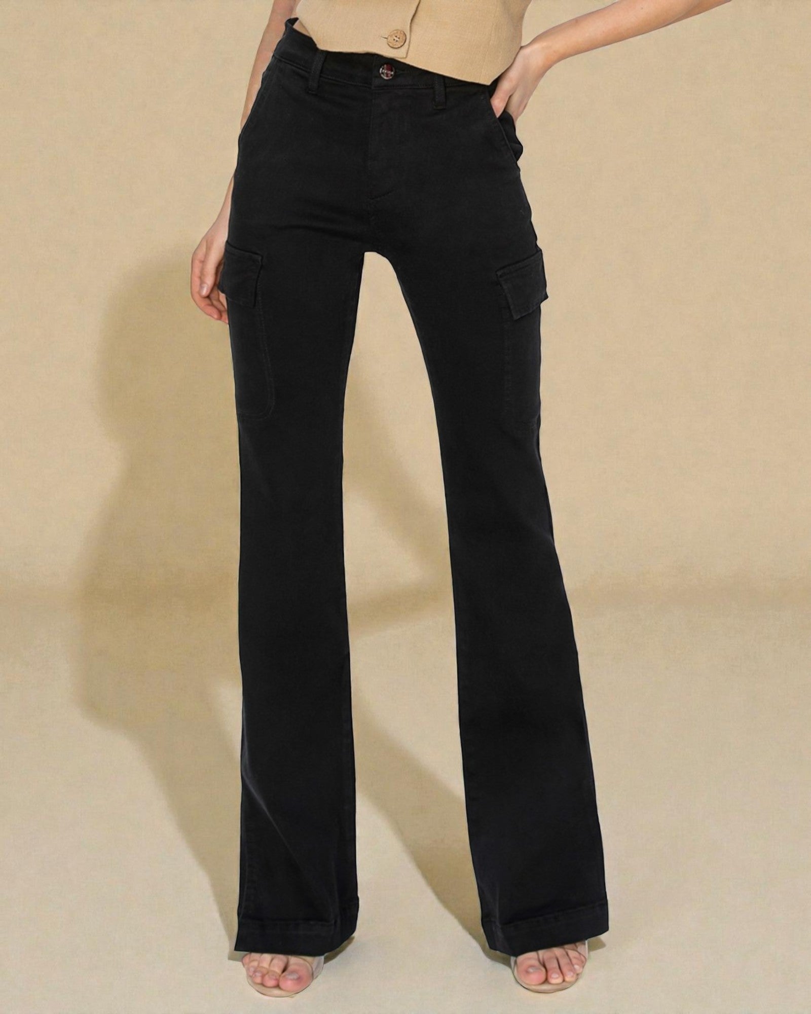 Person wearing black flared jeans on a beige background