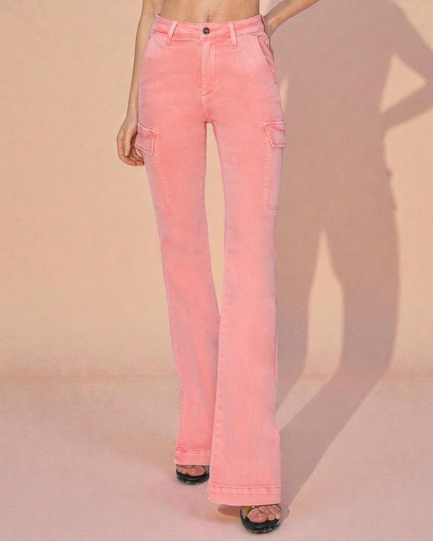 Pink flared jeans worn by a person on a beige background