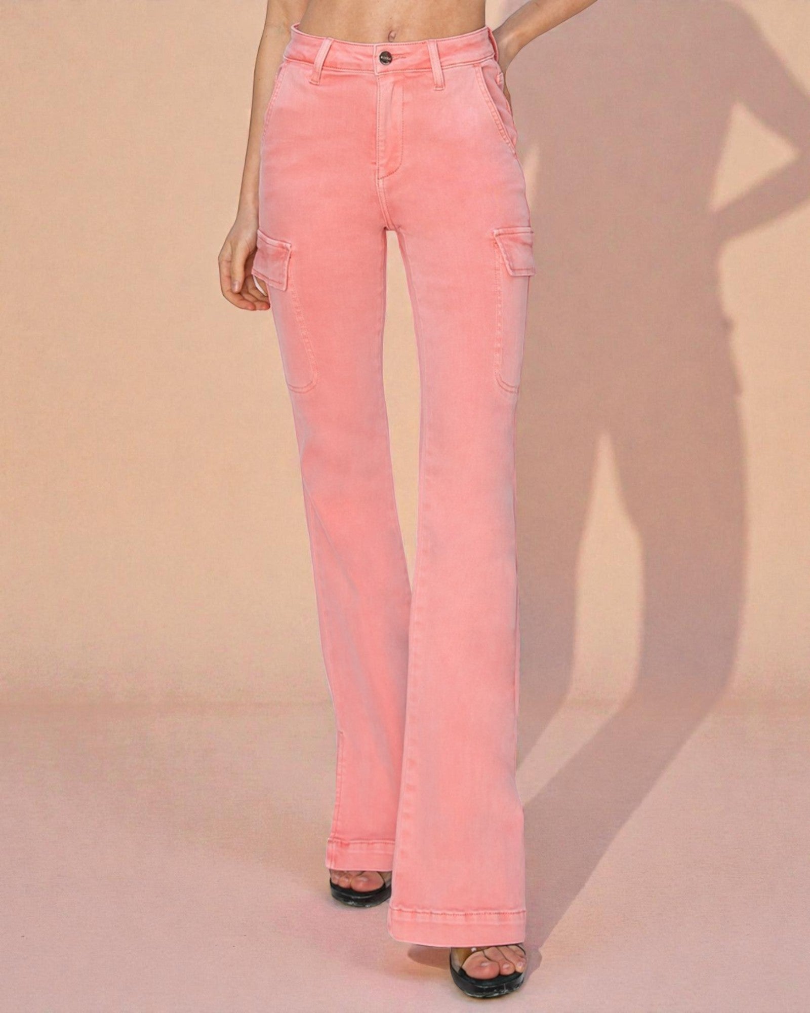 Pink flared jeans worn by a person on a beige background