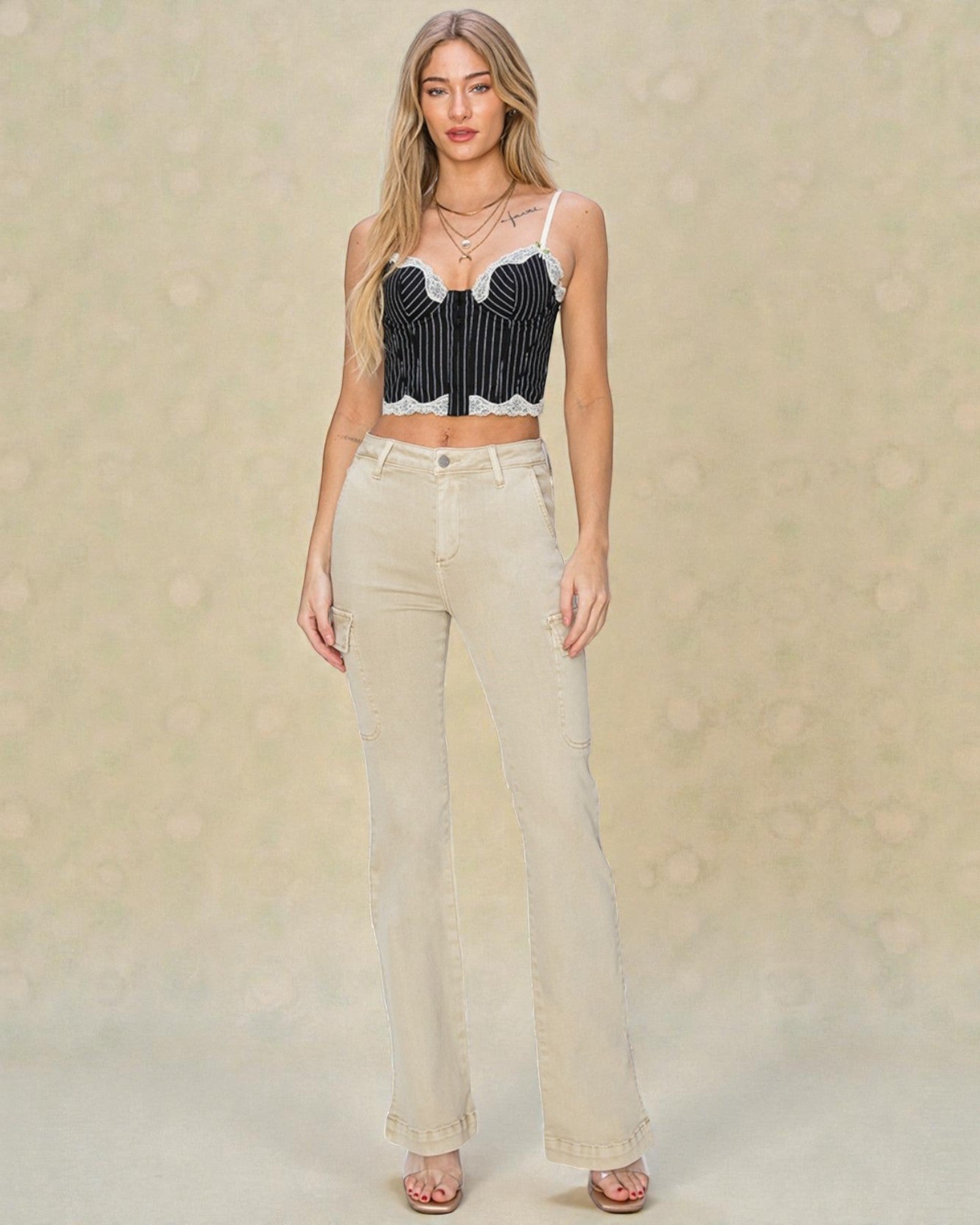 Woman wearing a black and white striped crop top and beige pants on a beige background