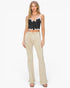 A woman modeling a black and white striped crop top with white lace trim and beige high-waisted flared jeans against a plain white background.