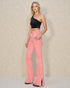 Woman wearing a black top and pink pants against a neutral background