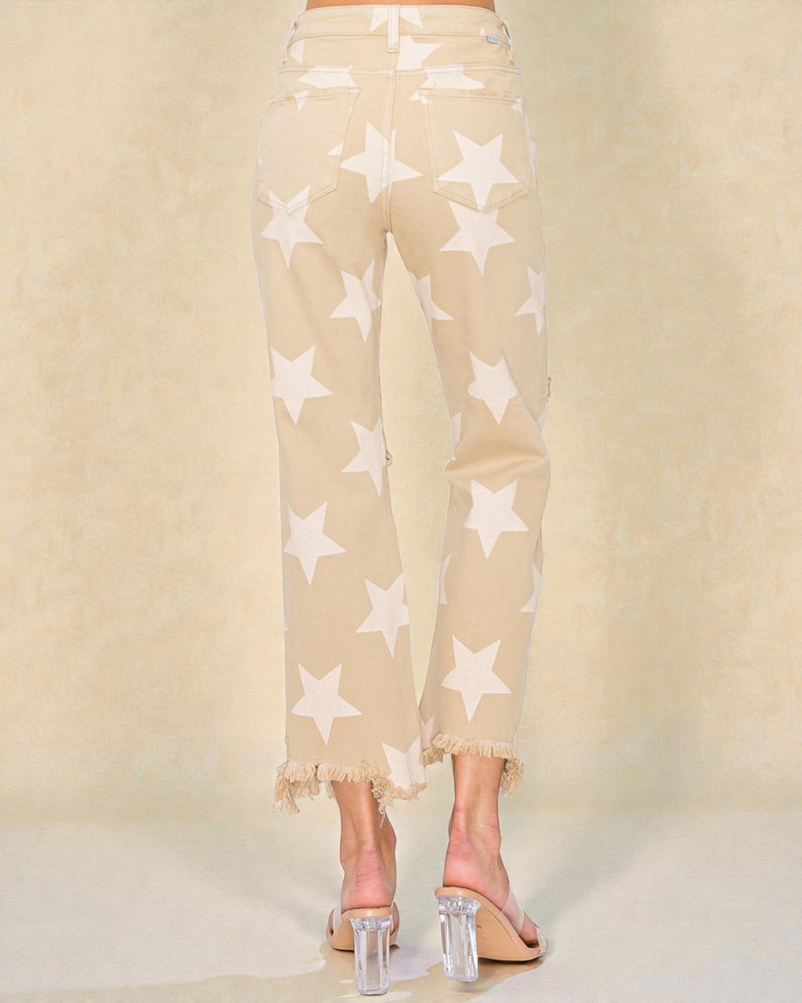 Beige pants with star pattern worn by a person on a beige background