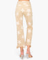 Back view of a model wearing beige cropped jeans with a white star pattern and frayed hems, paired with clear high-heeled sandals.