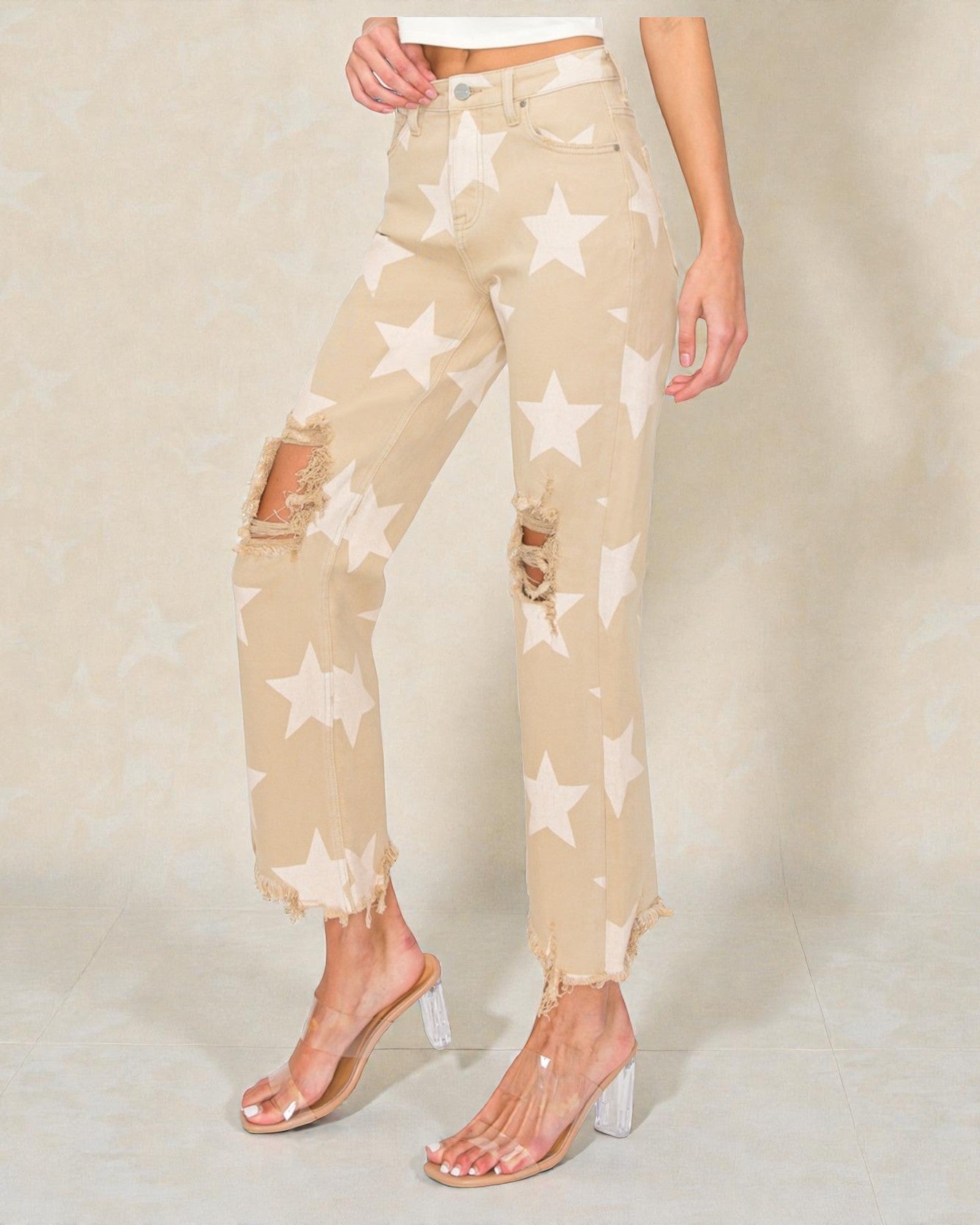 Beige pants with star patterns worn by a person on a neutral background