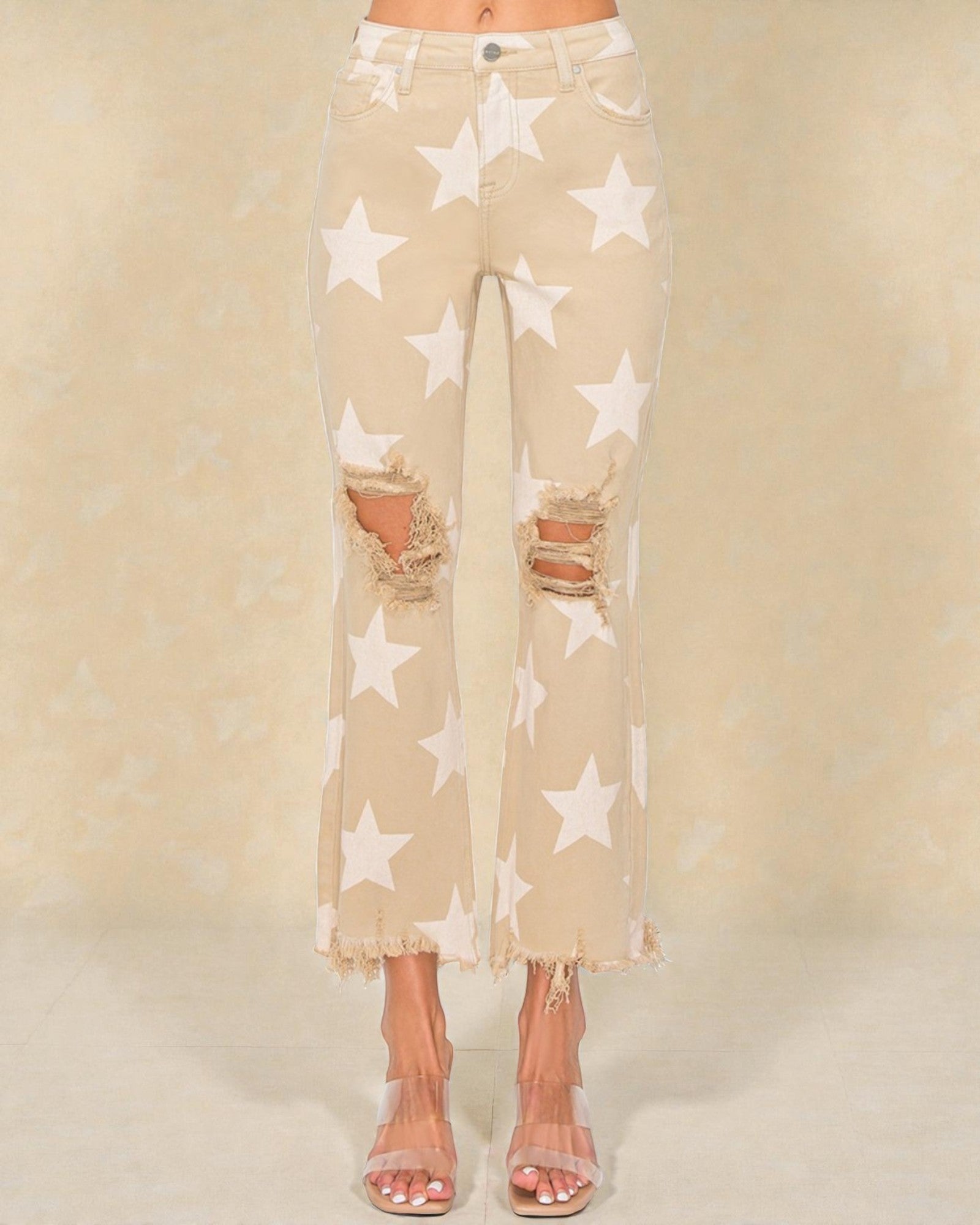 Beige pants with star pattern and distressed details on a beige background