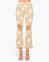A pair of beige cropped flare jeans with a white star pattern, featuring distressed rips at the knees and a frayed hem, shown on a model wearing clear high-heeled sandals.