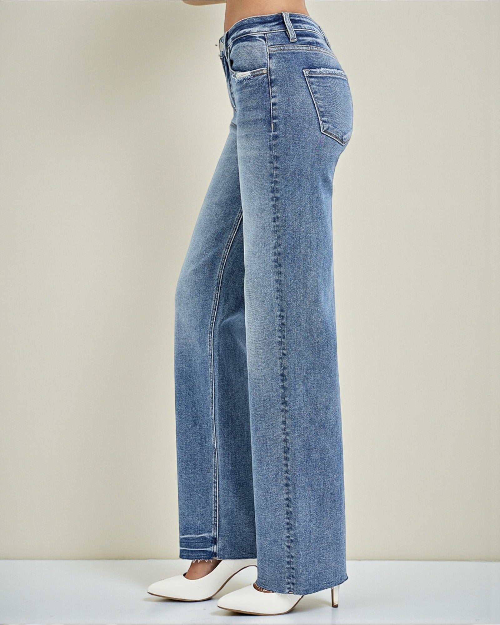 Blue jeans worn by a person on a plain background