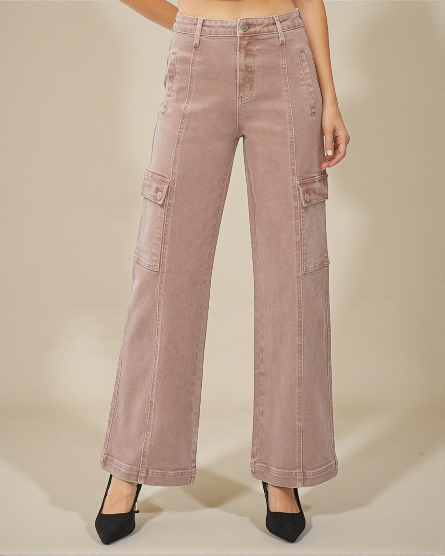 Pink cargo pants worn by a person on a beige background