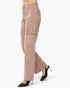 A side profile view of a person wearing dusty rose cargo jeans and black pointed-toe high heels with gold stiletto heels, set against a plain white studio background.