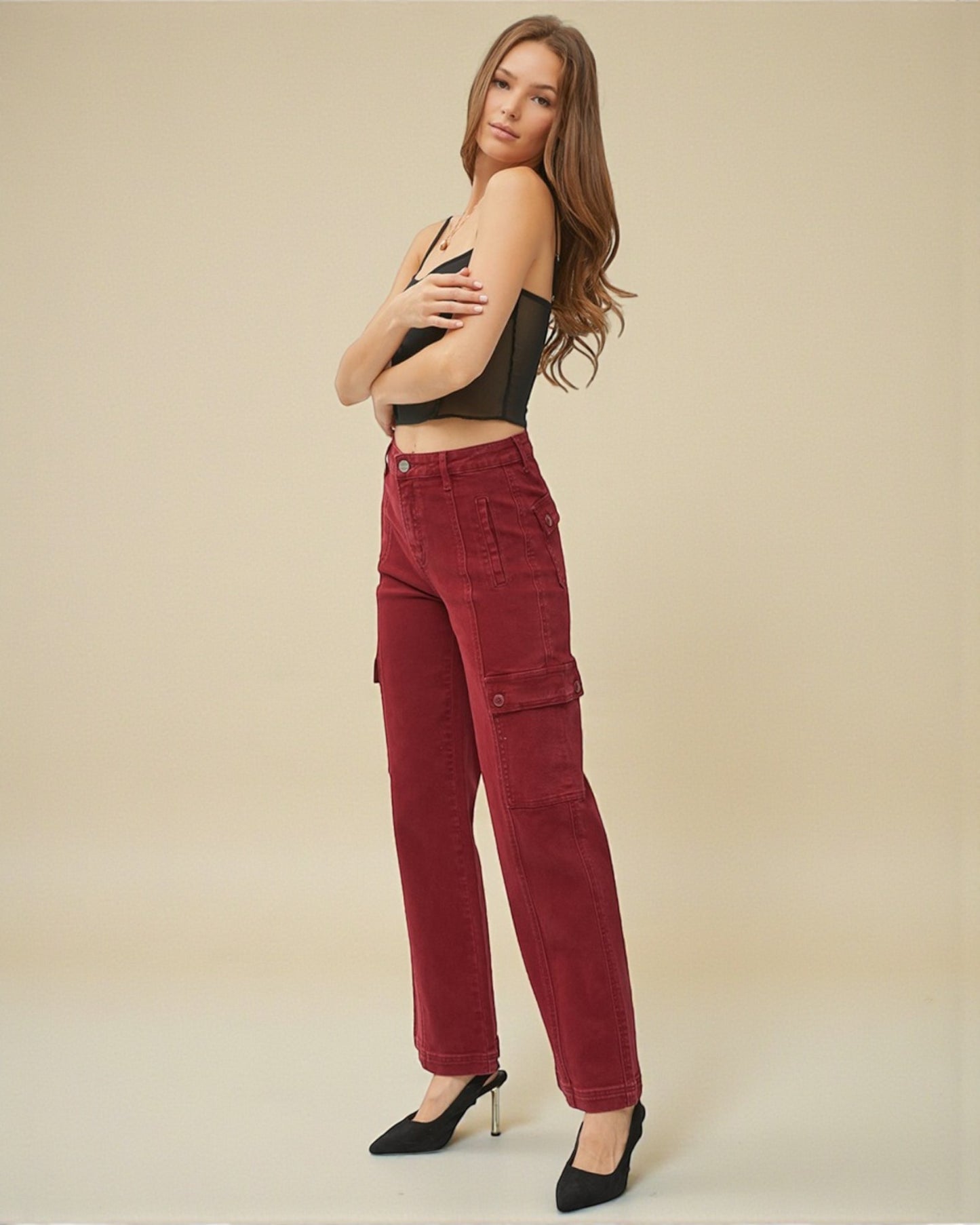 Woman wearing red cargo pants and a black top against a beige background