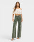 Woman wearing a white lace top and green jeans on a white background