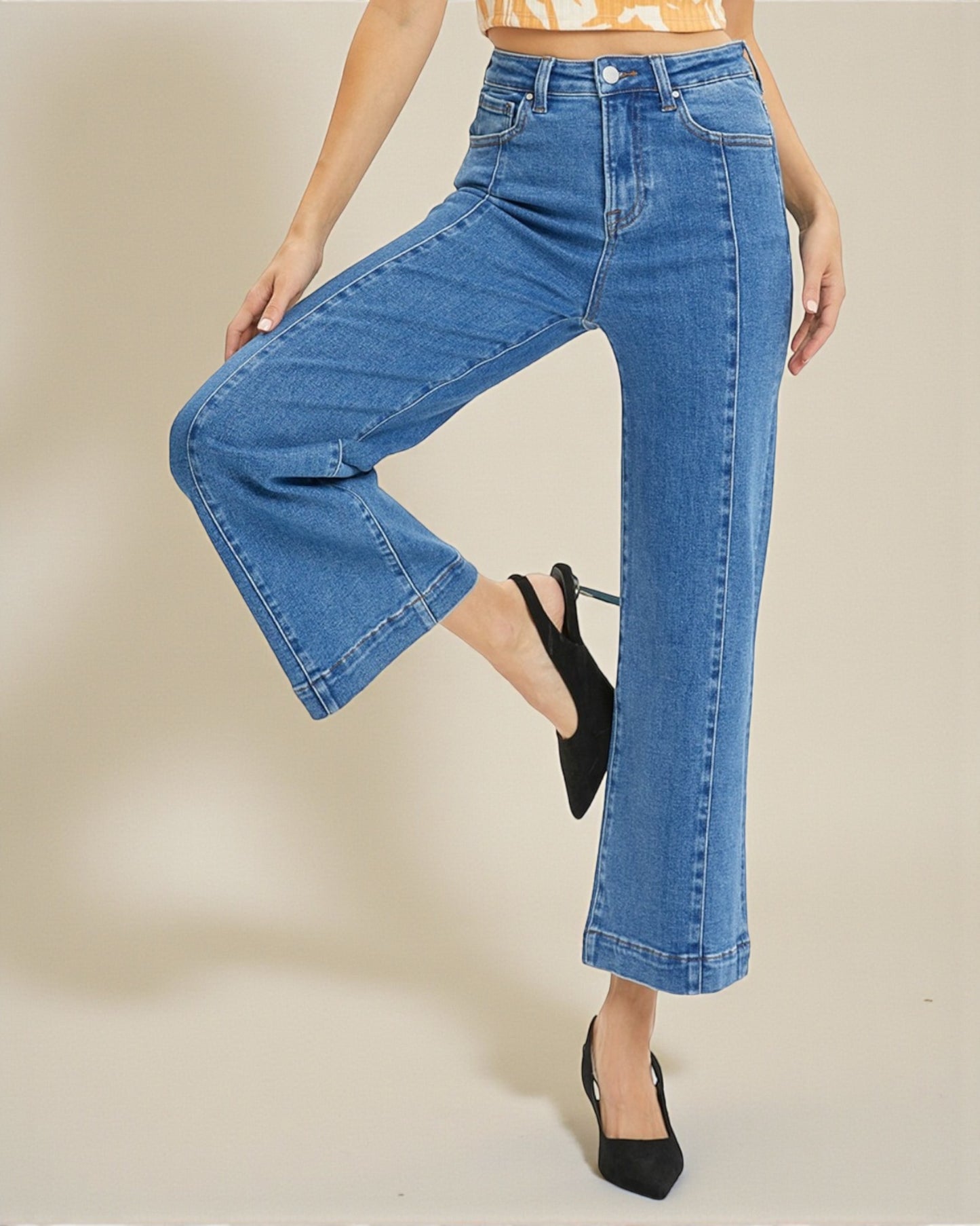 Person wearing blue wide-leg jeans on a beige background