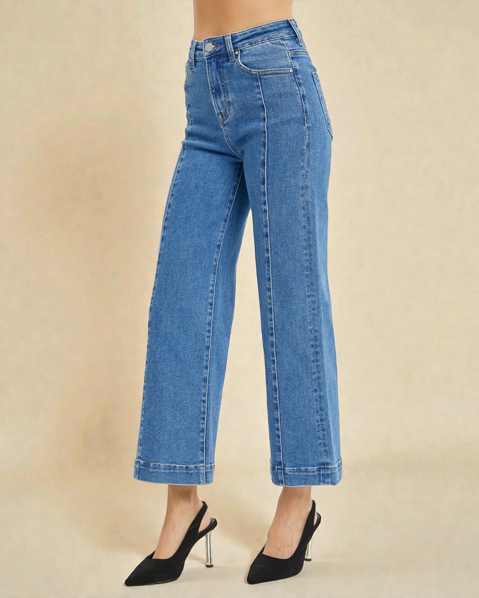 Blue jeans worn by a person on a beige background