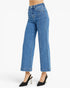 A model from the waist down wearing light blue cropped wide-leg jeans and black slingback high heels against a plain white studio background.