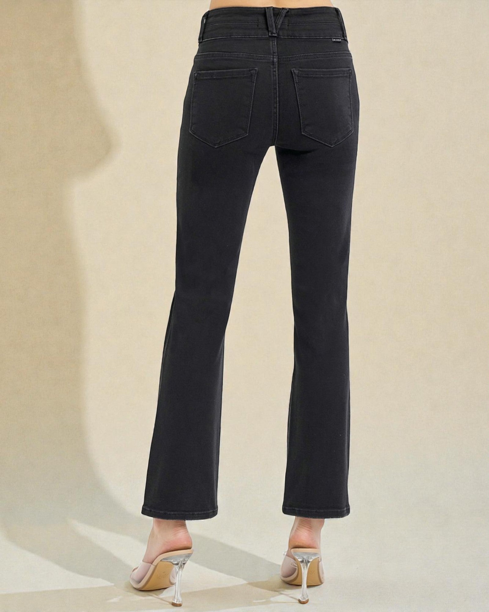 Black jeans worn by a person on a beige background