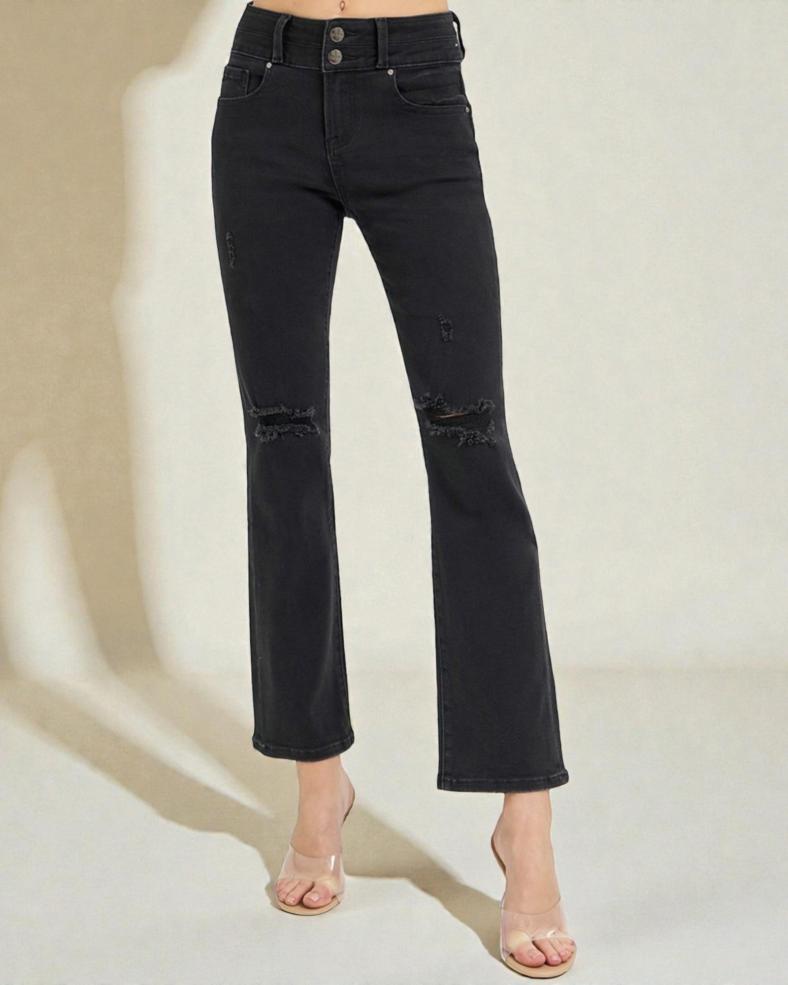 Black distressed jeans worn by a person on a neutral background