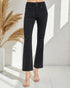 Black distressed jeans worn by a person in a minimalistic setting with a plant.