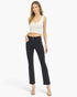 A woman modeling a white sleeveless crop top and black cropped flare jeans with distressed knee details, standing against a plain white studio background.