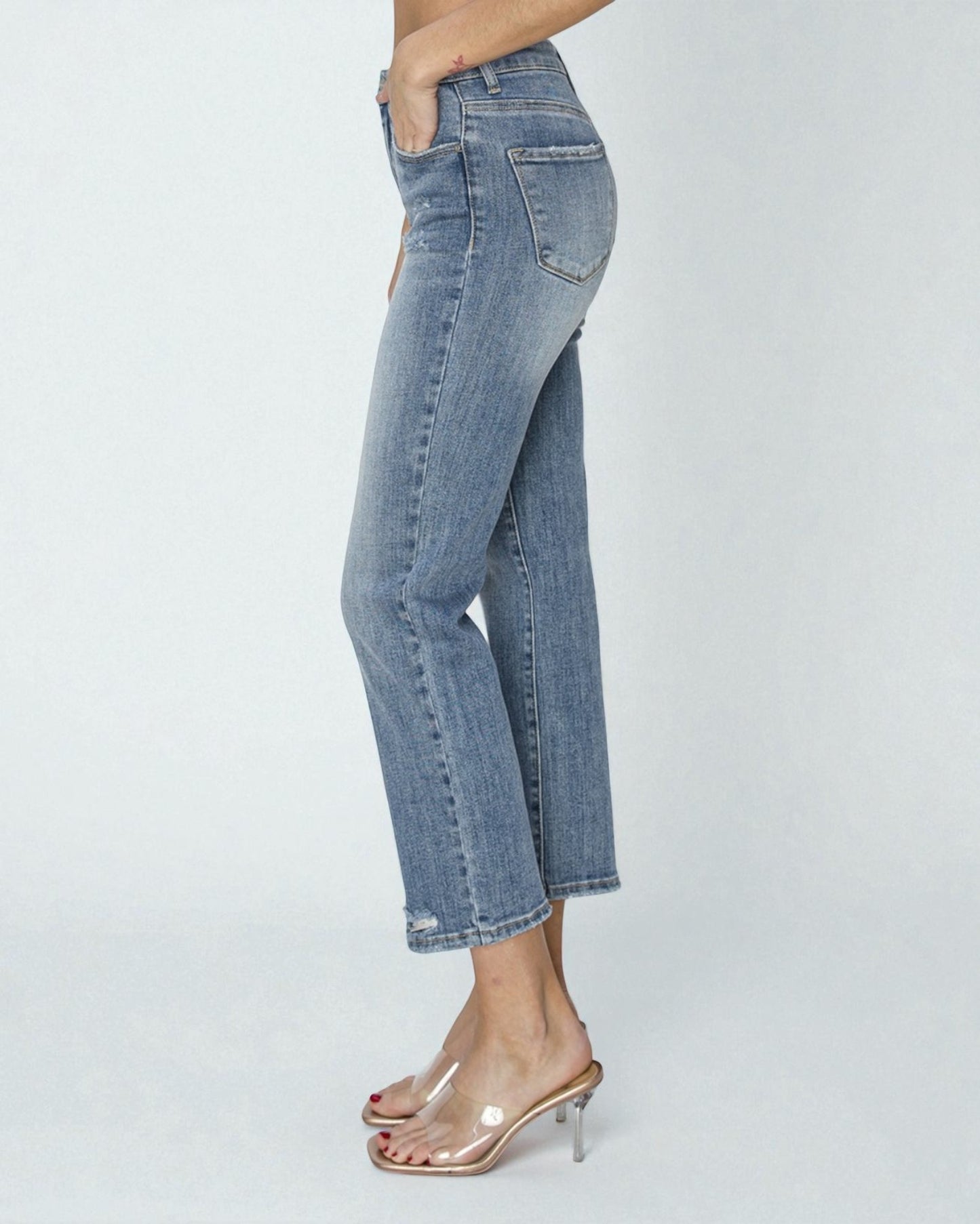 Person wearing blue jeans on a plain background